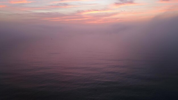 Luftaufnahme eines aufgehenden Meeres mit einer Decke aus Morgennebel und morgendlichen Sonnenstrahlen