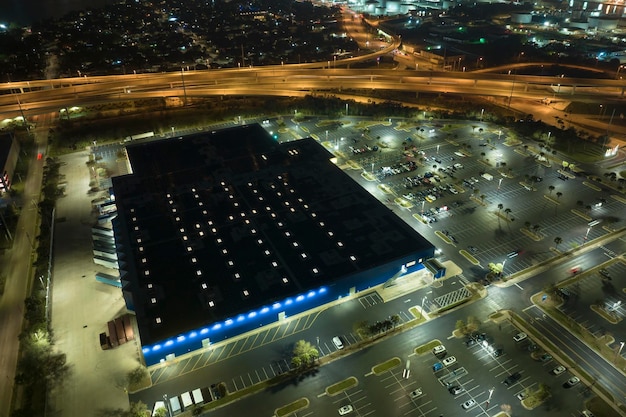 Luftaufnahme eines großen Parkplatzes bei Nacht mit vielen geparkten Autos Dunkler Parkplatz im Einkaufszentrum Supercenter mit Linien und Markierungen für Fahrzeugplätze und Richtungen