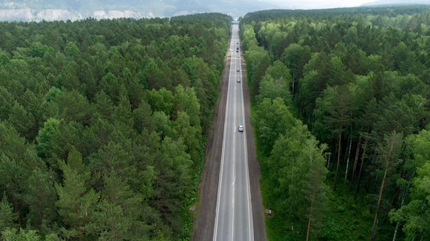 Luftaufnahme eines grünen Waldes und eines roten Autos auf der Straße. Reisekonzept aus der Vogelperspektive