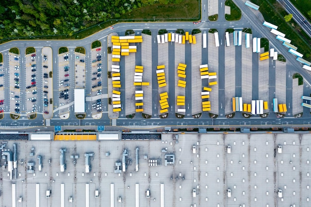 Luftaufnahme eines Lagers LKW mit Anhängern stehen auf einem Parkplatz in der Nähe eines Logistiklagers Lager eines Online-Shops ein Industriegebiet Blick aus großer Höhe