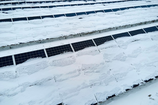 Luftaufnahme eines nachhaltigen Kraftwerks mit im Winter mit Schnee bedeckten Photovoltaikmodulen zur Erzeugung sauberer Energie Konzept der geringen Effektivität von erneuerbarem Strom im Norden