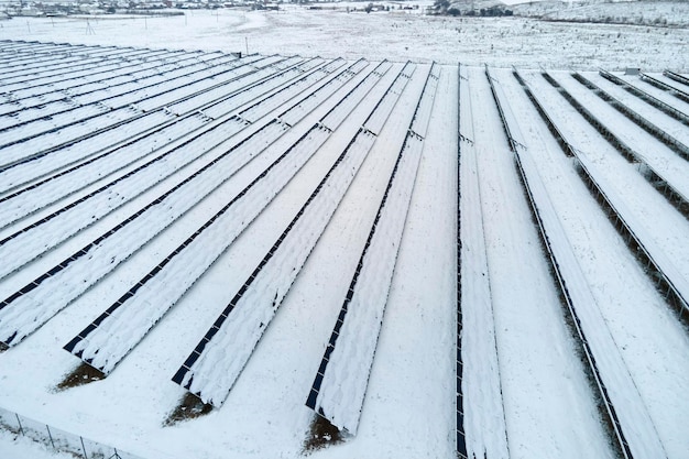 Luftaufnahme eines nachhaltigen Kraftwerks mit im Winter mit Schnee bedeckten Photovoltaikmodulen zur Erzeugung sauberer Energie Konzept der geringen Effektivität von erneuerbarem Strom im Norden