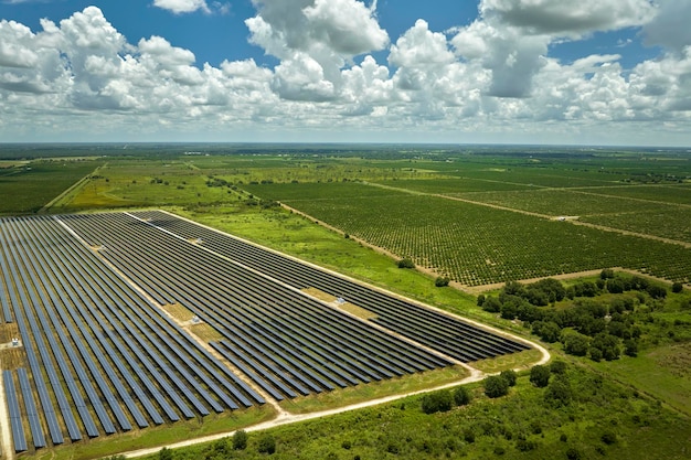 Luftaufnahme eines nachhaltigen Kraftwerks zwischen landwirtschaftlichen Ackerflächen mit Photovoltaikmodulen zur Erzeugung sauberer elektrischer Energie Konzept für erneuerbaren Strom ohne Emissionen