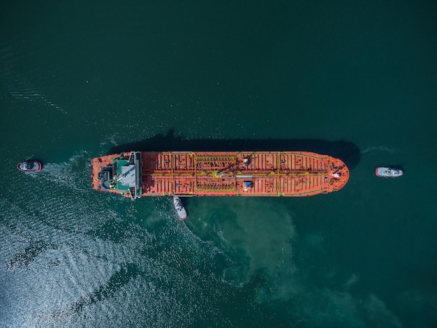 Luftaufnahme eines Tankschiffs mit eskortierendem Schlepper, der den Hafen verlässt