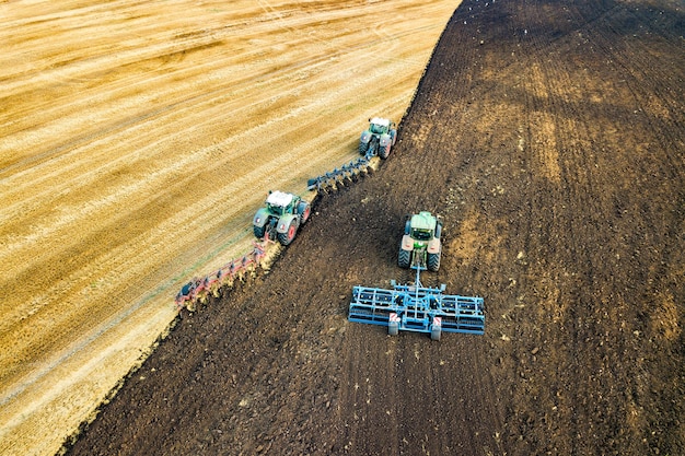 Luftaufnahme eines Traktors, der schwarzes landwirtschaftliches Feld nach der Ernte im Spätherbst pflügt