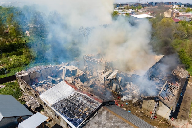 Luftaufnahme eines zerstörten Gebäudes in Brand mit eingestürztem Dach und aufsteigendem dunklem Rauch