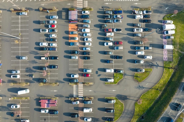 Luftaufnahme vieler bunter Autos, die auf dem Parkplatz mit Linien und Markierungen für Parkplätze und Wegbeschreibungen geparkt sind