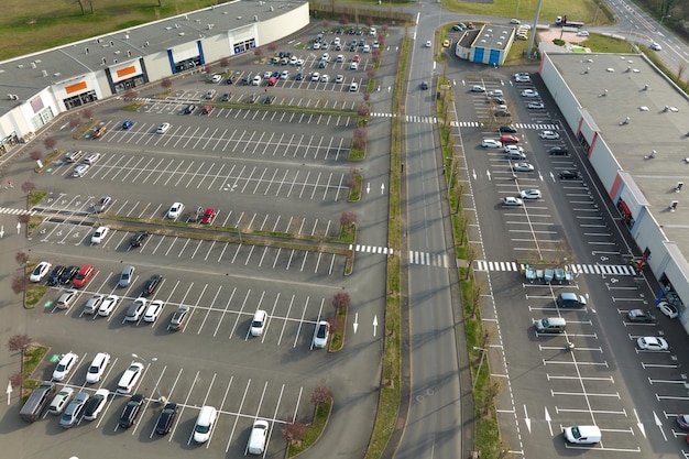 Luftaufnahme vieler bunter Autos, die auf dem Parkplatz mit Linien und Markierungen für Parkplätze und Wegbeschreibungen geparkt sind