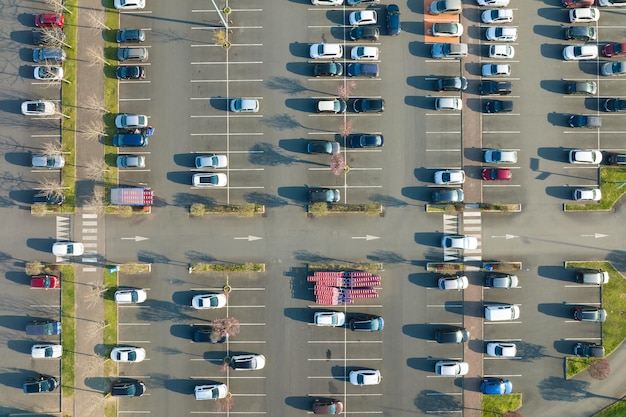 Luftaufnahme vieler bunter Autos, die auf dem Parkplatz mit Linien und Markierungen für Parkplätze und Wegbeschreibungen geparkt sind