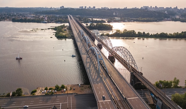 Luftaufnahme von Auto und Eisenbahn Darnitsky Brücke über Dnjepr Fluss