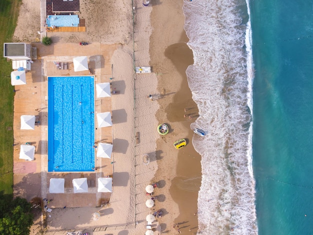 Luftaufnahme von der fliegenden Drohne der Menschenmenge, die sich am Strand mit Swimmingpool in Bulgarien entspannt