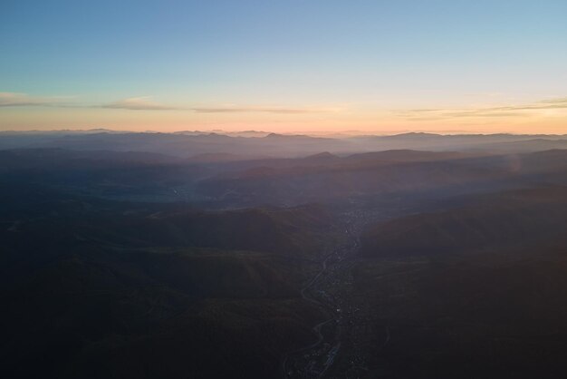 Luftaufnahme von dunklen Berghügeln bei Sonnenuntergang Dunstige Gipfel und neblige Täler am Abend