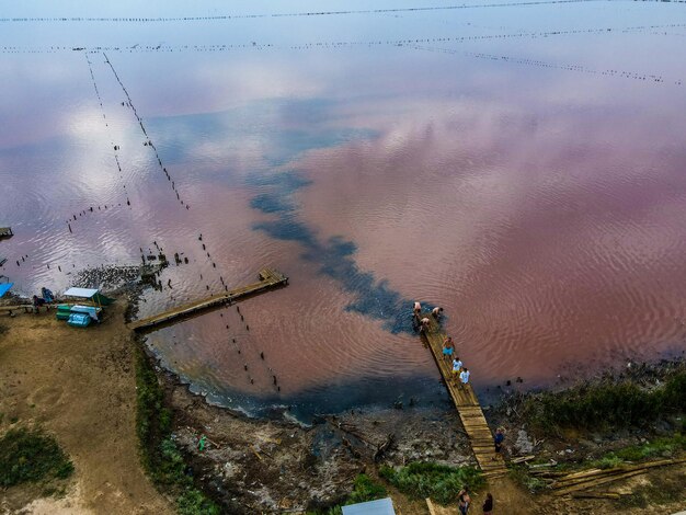 Luftaufnahme von einer Drohne auf Menschen, die im Freien in schmutzigem Wasser in rostiger Farbe baden