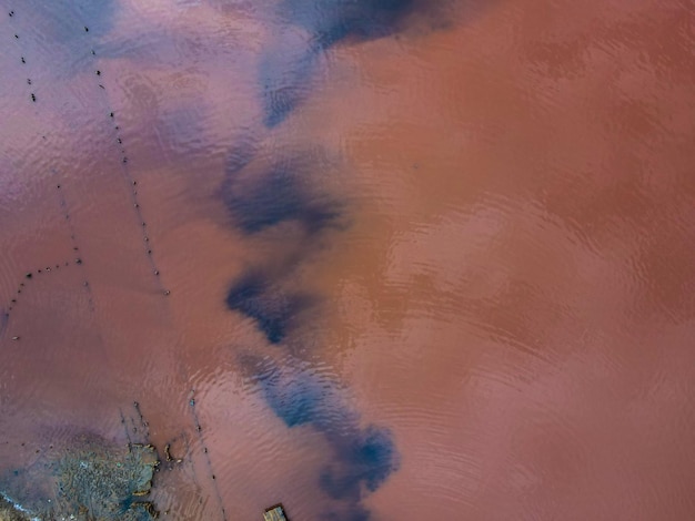 Luftaufnahme von einer Drohne auf Menschen, die im Freien in schmutzigem Wasser in rostiger Farbe baden