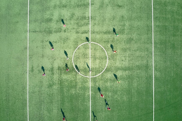 Luftaufnahme von Fußballspielern, die Fußball auf dem grünen Sportstadion spielen.
