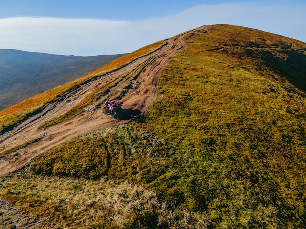 Luftaufnahme von Geländewagen-Offroad-Reisen, die durch Berghügel-Kopienraum-Herbstsaison über den Wolken klettern