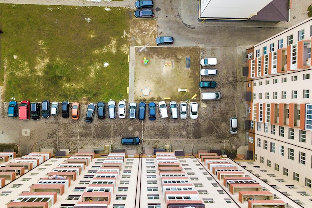 Luftaufnahme von geparkten Autos auf dem Parkplatz zwischen hohen Wohnhäusern.