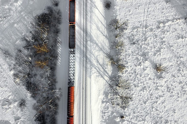 Luftaufnahme von Güterzug-Kesselwagen auf zweigleisiger Schienenstraße mit weißem Schnee in der Winteroberansicht