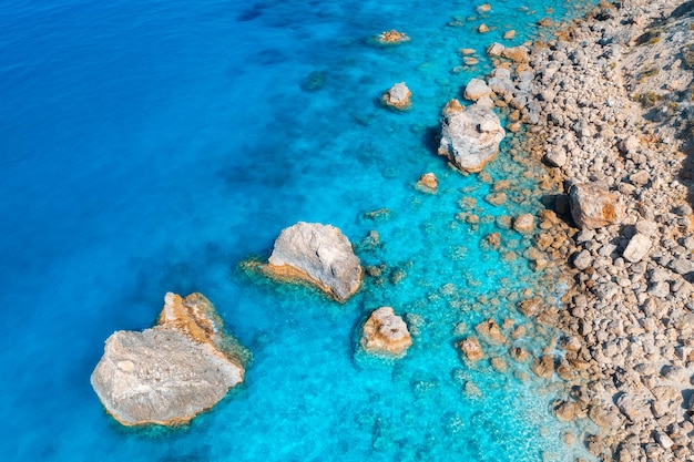 Luftaufnahme von klaren, blauen Meer Steinen und Felsen im Wasser leeren Strand bei Sonnenuntergang Sommer auf der Insel Lefkada Griechenland Tropische Meereslandschaft mit azurblauem Wasser Draufsicht auf die Küste Natur Hintergrund Reisen