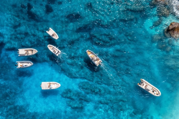 Luftaufnahme von kleinen Motorbooten im blauen Meer an einem sonnigen, hellen Tag im Sommer, Insel Sardinien, Italien, Drohnenaufnahme von Schnellbooten, Yachten, felsige Meeresküste, transparentes Wasser, Reisen, wunderschöne Meereslandschaft