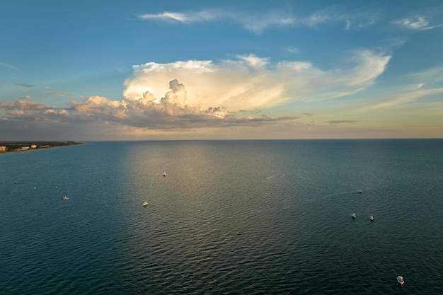 Luftaufnahme von kleinen Yachten bei Sonnenuntergang, die auf Seewellen mit Wellenoberfläche schwimmen, Motorboote, Erholung an der Meeresoberfläche