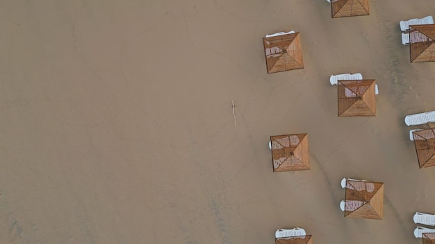 Luftaufnahme von Liegestühlen und Strohschirme am Strand ohne Menschen am Morgen am Strand
