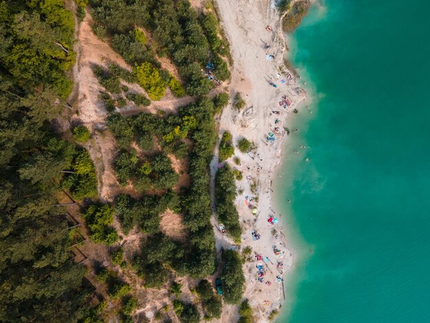 Luftaufnahme von Menschen, die in blauem, azurblauem Wasser schwimmen und sich am Sandstrand ausruhen, kopieren Sie Platz direkt darüber