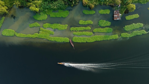 Luftaufnahme von oben Bewegungsunschärfe Longtail-Boot mit voller Geschwindigkeit und Spritzwasserlinie im Flussufer