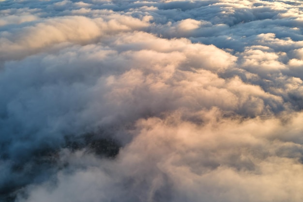 Luftaufnahme von oben in großer Höhe von dichten, geschwollenen Kumuluswolken, die abends fliegen. Erstaunlicher Sonnenuntergang aus der Sicht des Flugzeugfensters