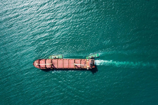 Luftaufnahme von oben Schlepper ziehen Ölschiffstanker auf grünem Meer, das zur Reparatur der Werft geht