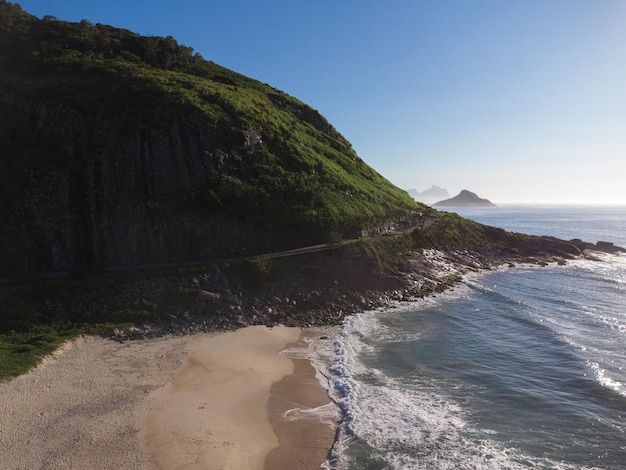 Luftaufnahme von Prainha Beach, ein Paradies in Rio de Janeiro, Brasilien. Große Hügel herum. Im Hintergrund die Strände von Recreio dos Bandeirantes. Sonniger Tag im Morgengrauen. Grünliches Meer. Drohnenfoto.