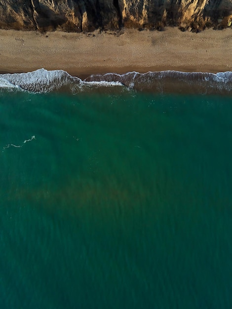 Luftaufnahme von Sandstrand und Meer mit Wellen Draufsicht