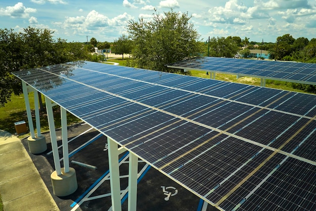 Luftaufnahme von Sonnenkollektoren, die als Schattendach über einem Parkplatz für geparkte Autos installiert wurden, um eine effektive Erzeugung sauberer Elektrizität zu ermöglichen. In die städtische Infrastruktur integrierte Photovoltaik-Technologie