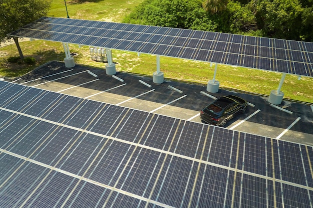 Luftaufnahme von Sonnenkollektoren, die als Schattendach über Parkplätzen für geparkte Autos installiert sind, um effektiv sauberen Strom zu erzeugen. Photovoltaiktechnologie integriert in städtische Infrastruktur