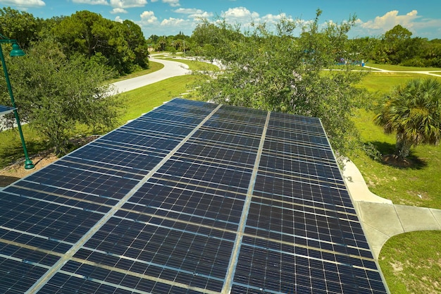 Luftaufnahme von Sonnenkollektoren, die als Schattendach über Parkplätzen für geparkte Autos installiert sind, um effektiv sauberen Strom zu erzeugen. Photovoltaiktechnologie integriert in städtische Infrastruktur