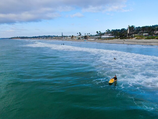 Luftaufnahme von Surfern, die auf die Wellen im blauen Wasser warten. Del Mar Beach, Kalifornien, USA.