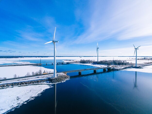 Luftaufnahme von Windmühlen mit blau gefrorenem Fluss im Schnee Winter Finnland Windkraftanlagen für Strom mit sauberer und erneuerbarer Energie