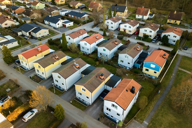 Luftaufnahme von Wohnhäusern mit roten Dächern und Straßen mit geparkten Autos im ländlichen Stadtgebiet.