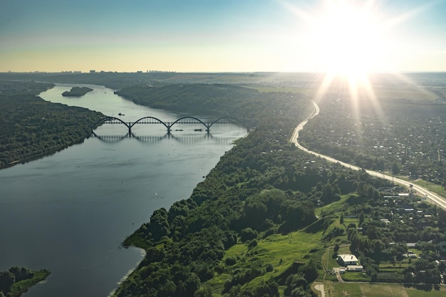 Luftaufnahmen aus einem Flugzeugfenster Flugzeugflug über Fluss mit Brücke bei Sonnenuntergang