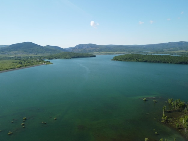 Luftbild auf dem Wasserreservoir im Bergtal mit schöner Aussicht auf den grünen Frühlingswald