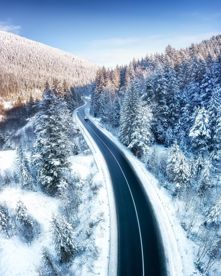 Luftbild auf der Straße und im Wald zur Winterzeit Natürliche Winterlandschaft aus der Luft Wald unter Schnee und zur Winterzeit Landschaft aus der Drohne