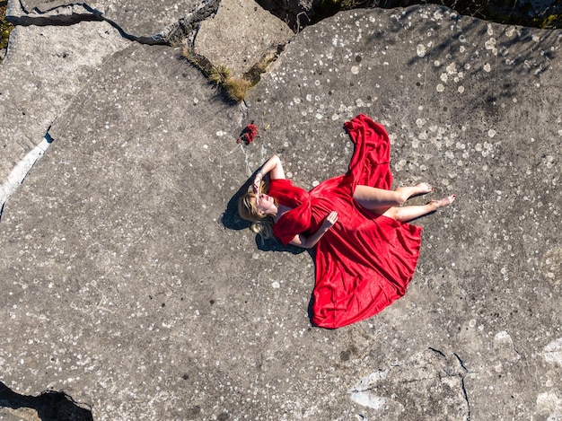 Luftbild auf Mädchen in rotem Kleid auf Felsen oder Beton ruiniert