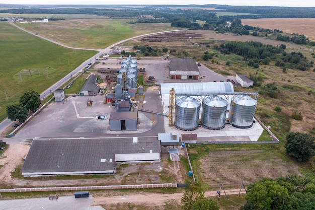 Luftbild auf Reihen von Agro-Silos Getreideaufzug mit Saatgut-Reinigungslinie in einer riesigen Agroprocessing-Produktionsanlage zur Verarbeitung von Trocknungsreinigung und Lagerung von landwirtschaftlichen Produkten