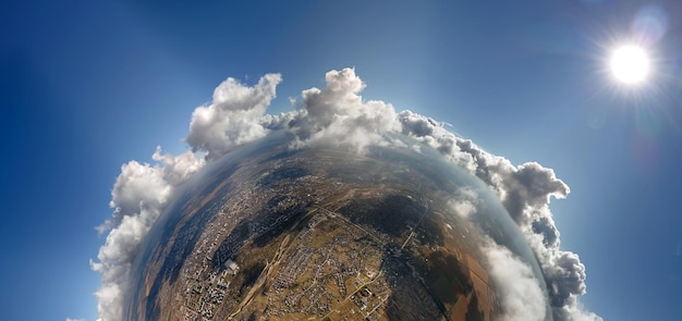 Luftbild aus großer Höhe des kleinen Planeten mit entfernter Stadt, die mit geschwollenen Cumulus-Wolken bedeckt ist, die vor dem Regensturm vorbeifliegen Flugzeug-Sicht auf die Landschaft bei bewölktem Wetter