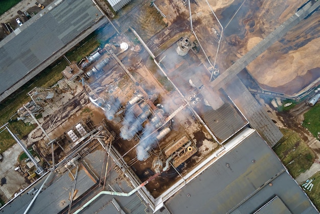 Luftbild der Holzverarbeitungsfabrik mit Rauch aus dem Produktionsprozess, der die Atmosphäre auf dem Werkshof verschmutzt