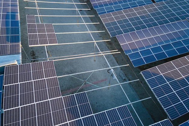 Luftbild des Solarkraftwerks mit blauen Photovoltaikmodulen, die auf dem Dach des Industriegebäudes zur Erzeugung von grünem Ökostrom montiert sind Produktion eines nachhaltigen Energiekonzepts