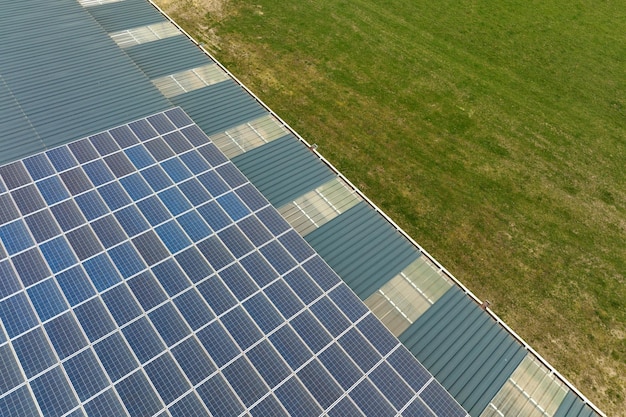 Luftbild des Solarkraftwerks mit blauen Photovoltaikmodulen, die auf dem Dach des Industriegebäudes zur Erzeugung von grünem Ökostrom montiert sind Produktion eines nachhaltigen Energiekonzepts