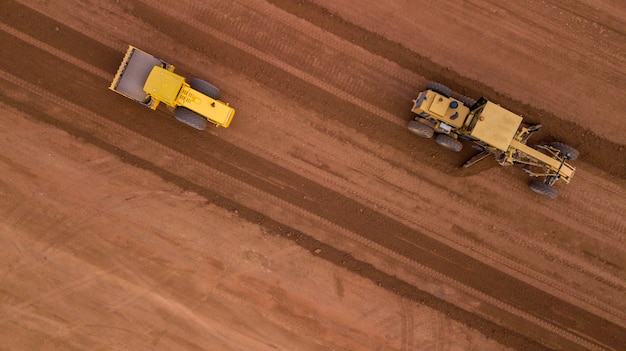 Luftbild gelber Bagger, der eine Autobahn baut Straßengrader schwere Erdbewegung Bulldozer arbeiten