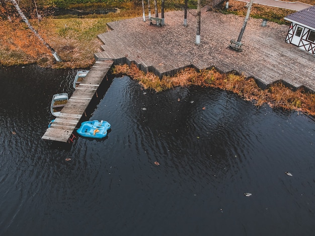 Luftbild-Pier mit Holzbooten am Ufer eines malerischen Sees, Herbstwald. St. Petersburg, Russland.