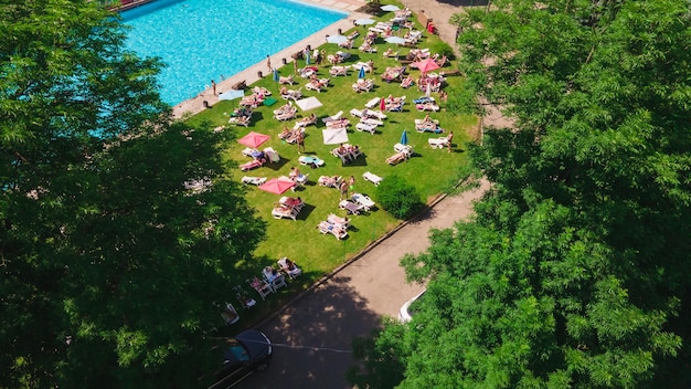 Luftbild von Menschen, die sich beim Sonnenbaden in der Nähe des Stadtpools im Freien im sonnigen Sommertag ausruhen